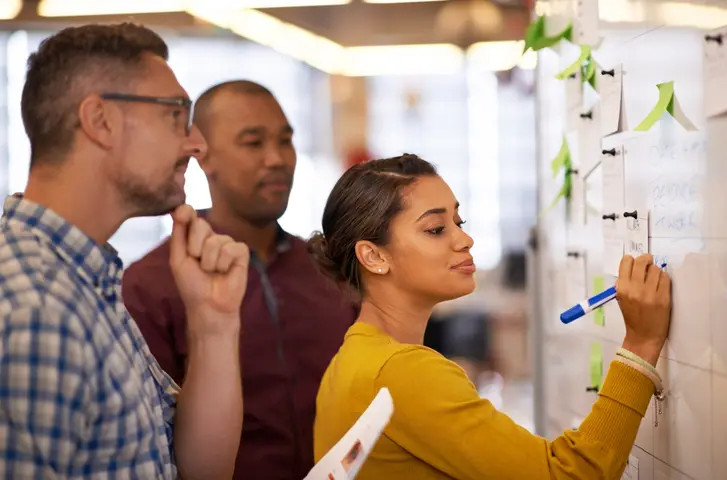 Shot of a group of coworkers brainstorming at a whiteboard